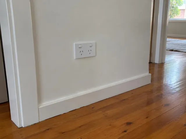 White double power point on a painted wall above timber floorboards in a home interior in Putney